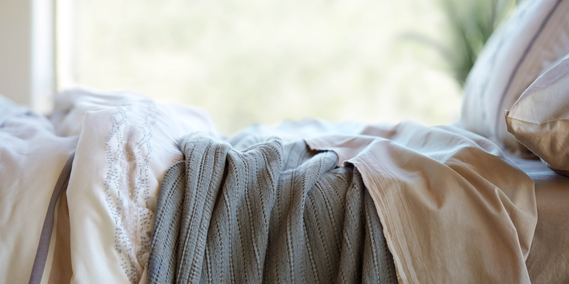 Side image of a made bed with the Sonoran Bundle. Image showcases a Sonoran Duvet Cover, Agave Ridgeback Coverlet, and Ochre Garment Washed Percale Sheets