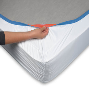 Image of the bottom of a mattress with a Cooling or Warming Mattress Protector on it. The image showcases the reversible blue and orange 1" elastic cuff on the protector. 