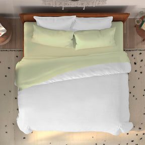 Top-down image of a dressed bed with Sage Bamboo Rayon Sheets and a white duvet cover 