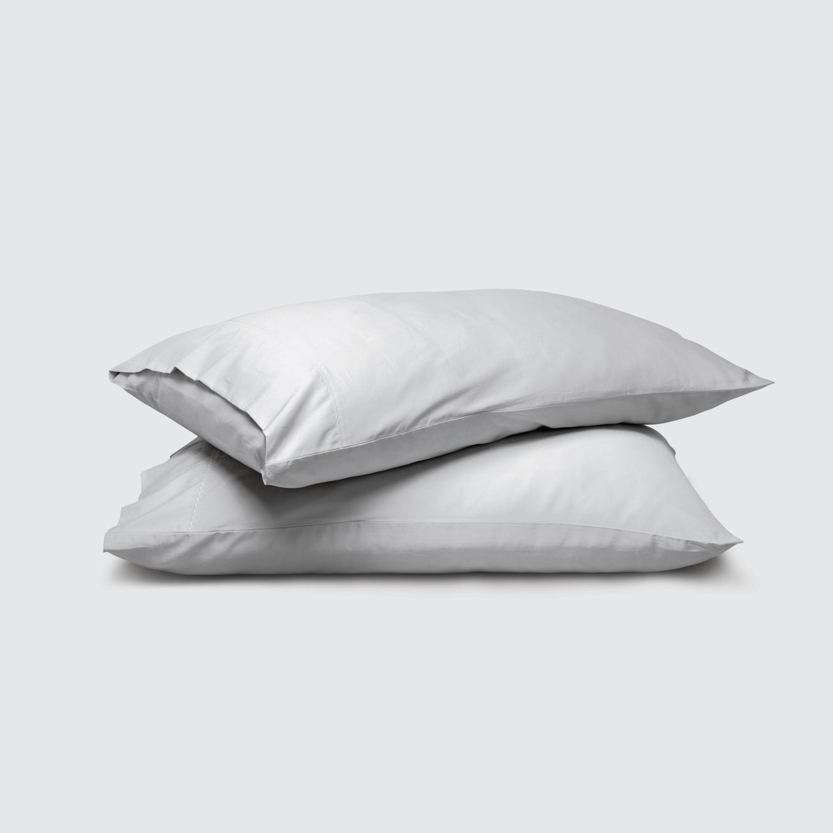 Image of two pillows stacked on top of one another with a Coastal Gray Weightless Cotton Pillowcase on each