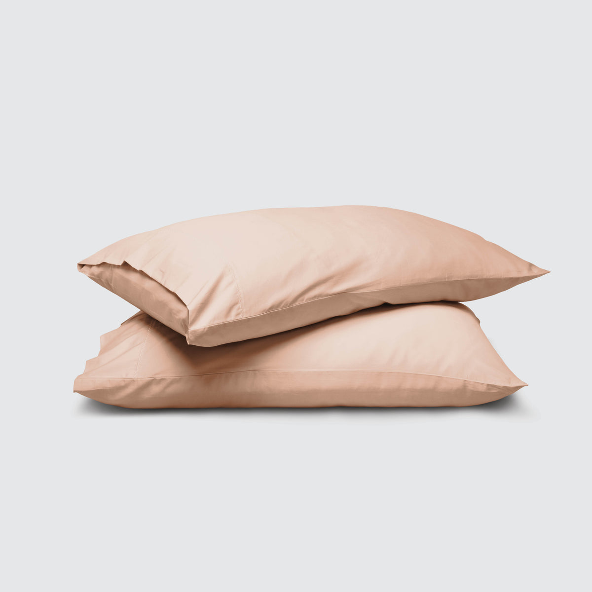 Image of two pillows stacked on top of one another with a Blush Pink Weightless Cotton Pillowcase on each