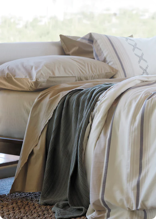 Image of a made bed with a large window behind it. The bed showcases Ochre Garment Washed Percale Sheets, an Agave Ridgeback Coverlet, and a Sonoran Duvet Cover.